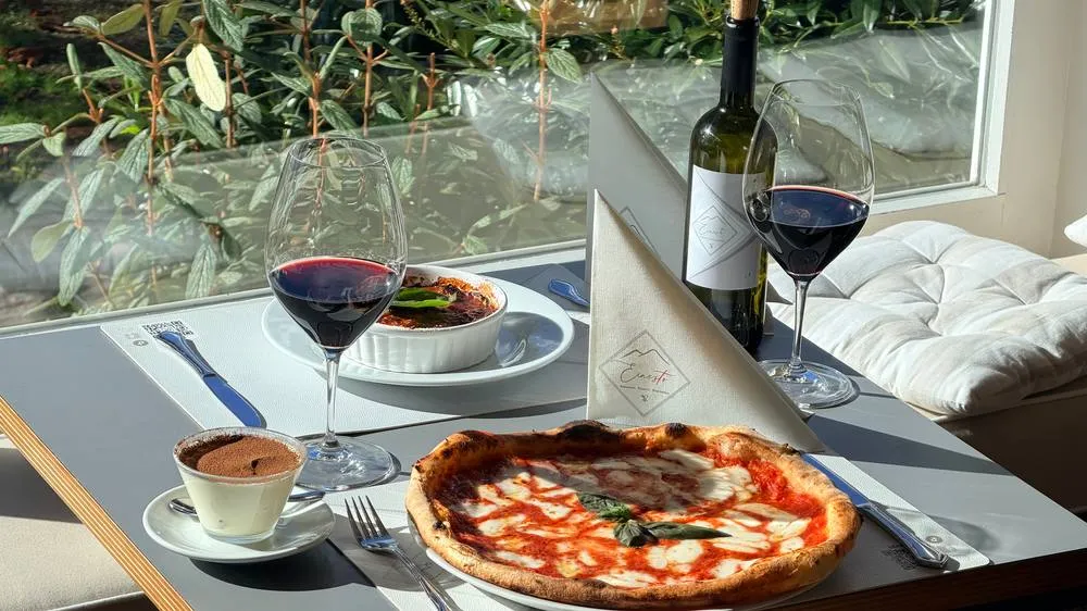 Pizza Margherita und Rotwein am Fenster des Clubrestaurants